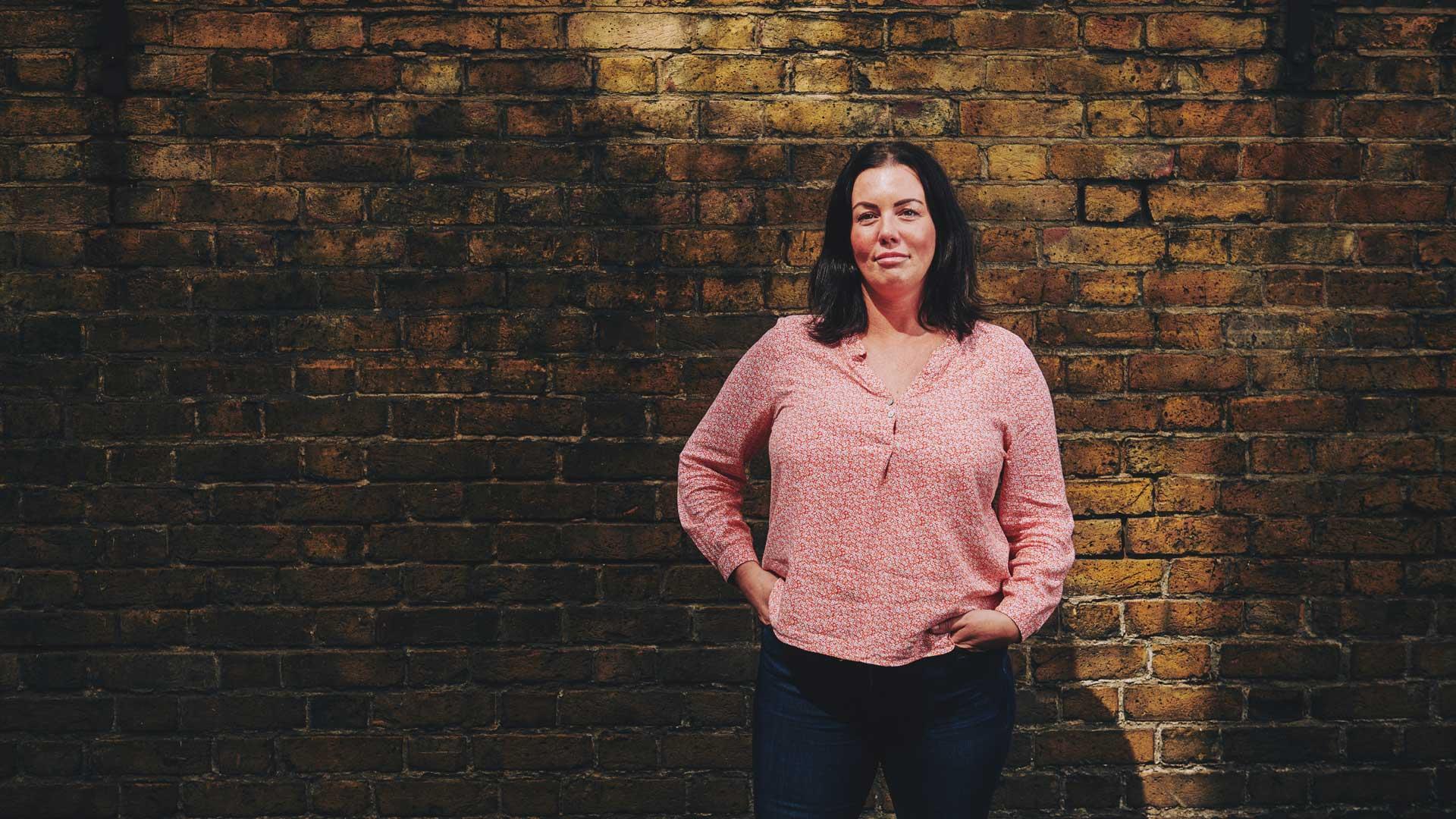 woman standing in front of a wall with her hands in her pockets