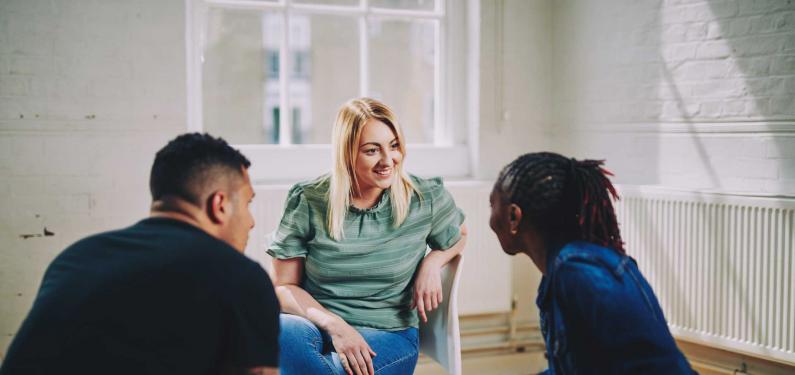 A woman and two men are sitting having a conversation