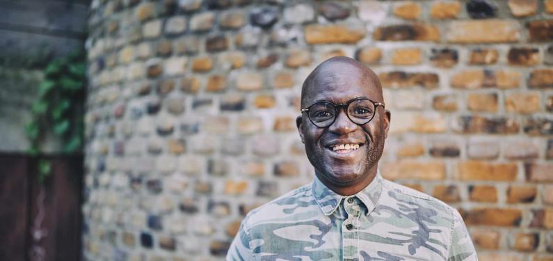 man smiling standing in front of a brick wall