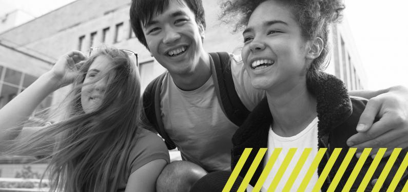 Three young people smiling and hugging