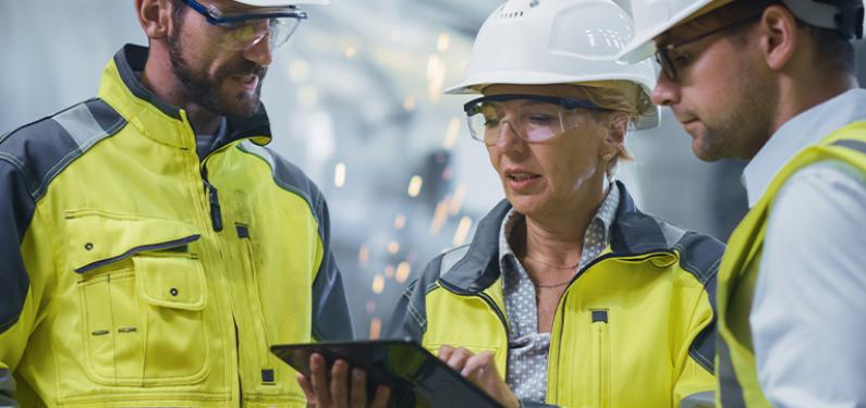 Two men and a woman wearing high visibility jackets and hard hats