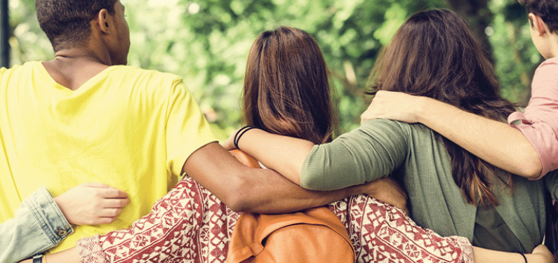 Five young people with their backs to the camera and arms around each other