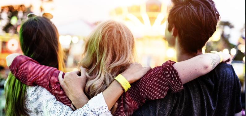 Trio of young people with their backs to the camera and their arms around each other