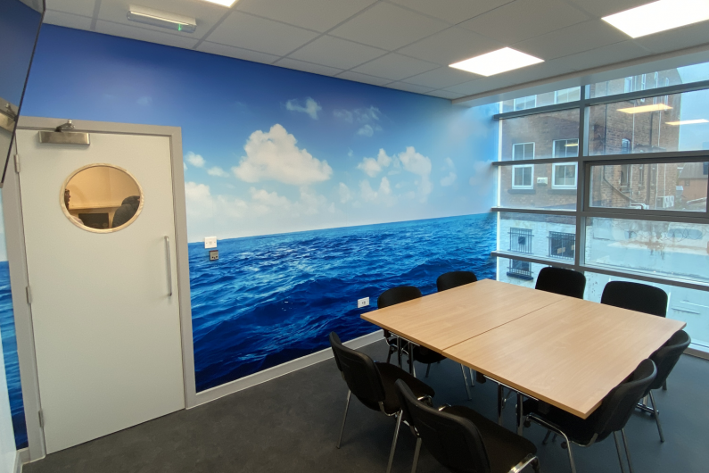A meeting room at the Wirral hub with a table, chairs and a TV screen