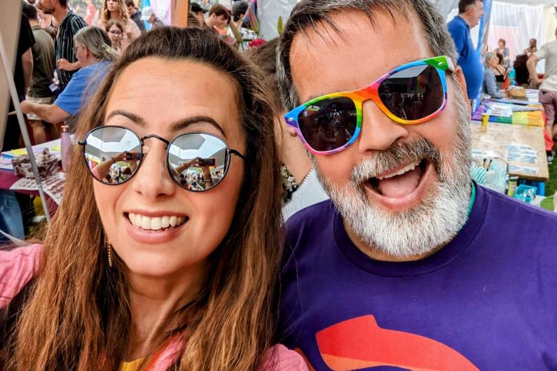 A man and a women taking a selfie and smiling at the camera. They are both wearing sunglasses