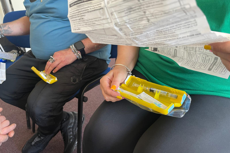 A yellow naloxone box is being held by a woman and the instructions are in her other hand