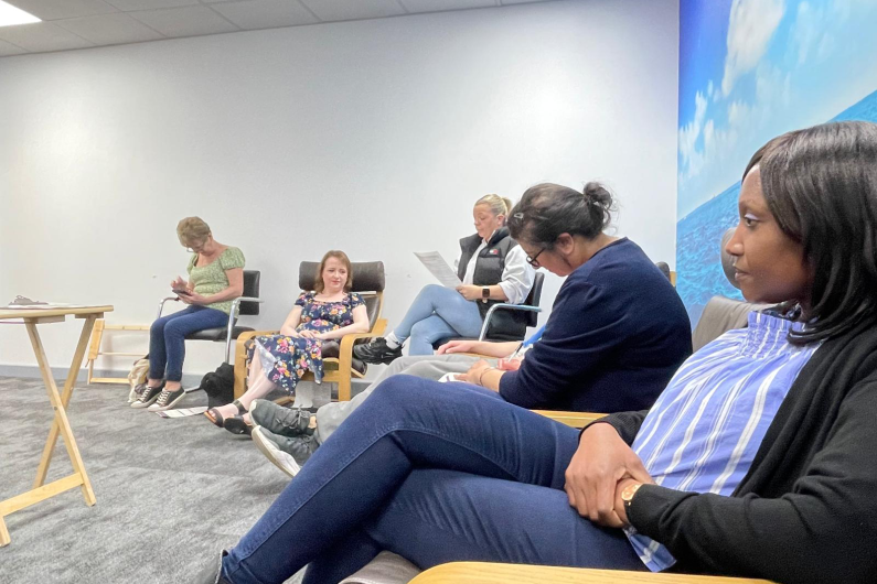 People sat around the edge of a room taking notes