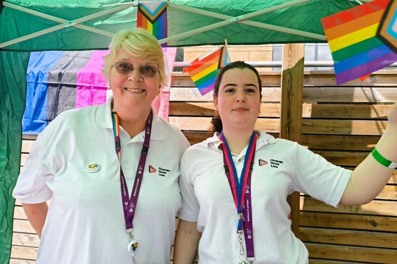 Two women stood under a gazebo wearing white t-shirts and purple lanyards