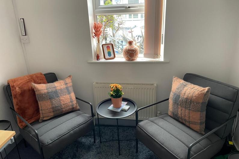 Two arm chairs place either side of a window with a small coffee table between them