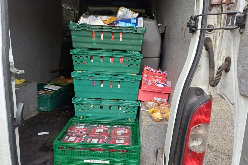 A stack of green crates full of food in the back of a van